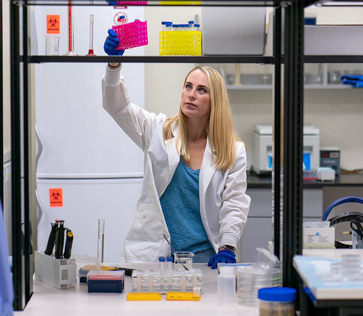 Woman grabbing a container of vials in a lab