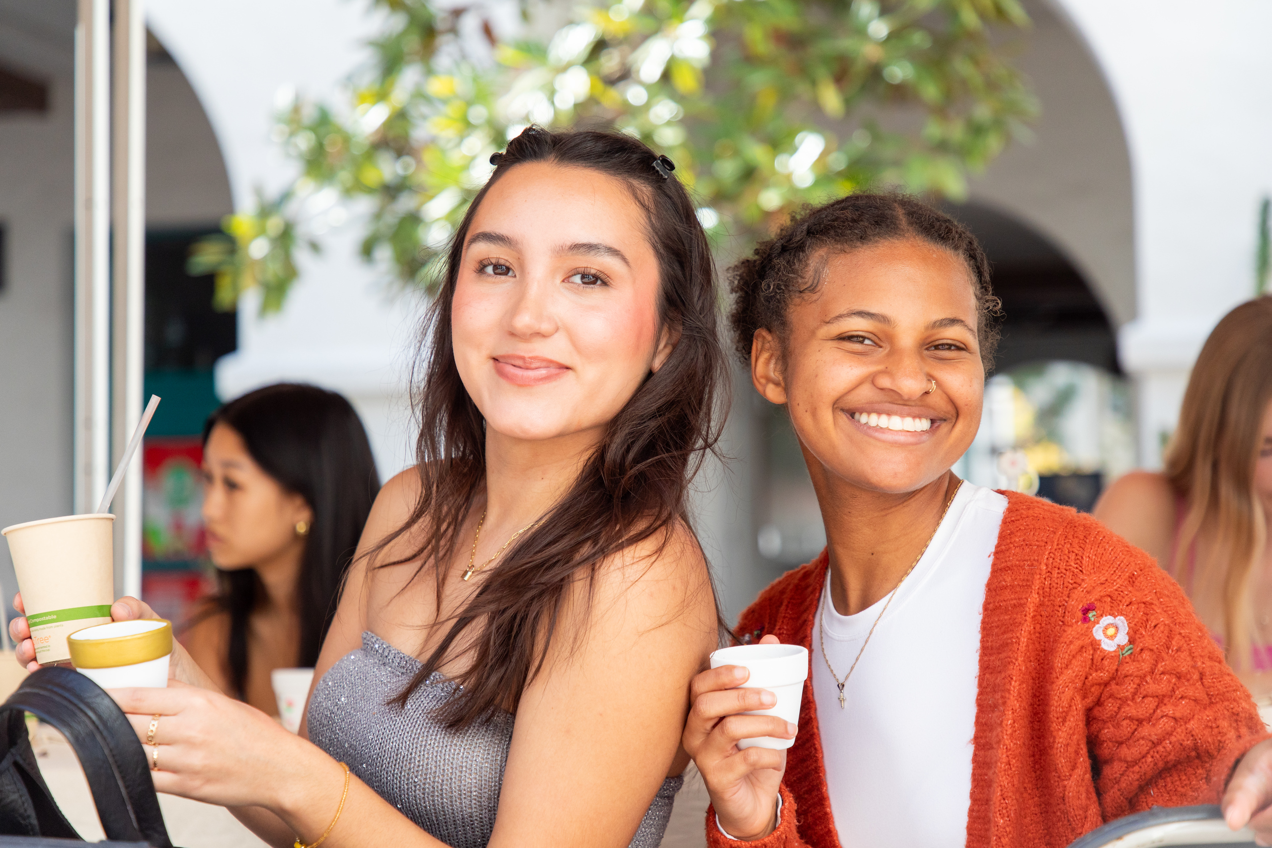 2 girls smiling holding a coffee