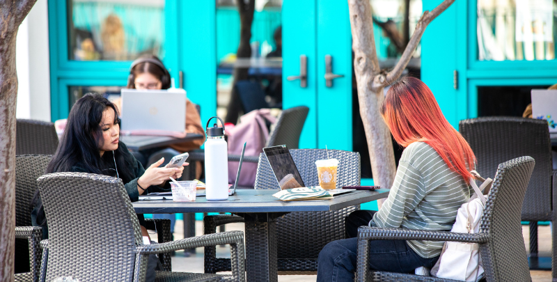 Girl sitting on a bench with a friend in front of her