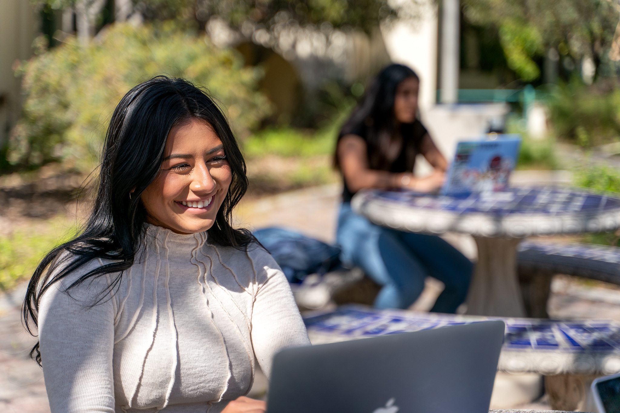 student smiling while looking at her laptop